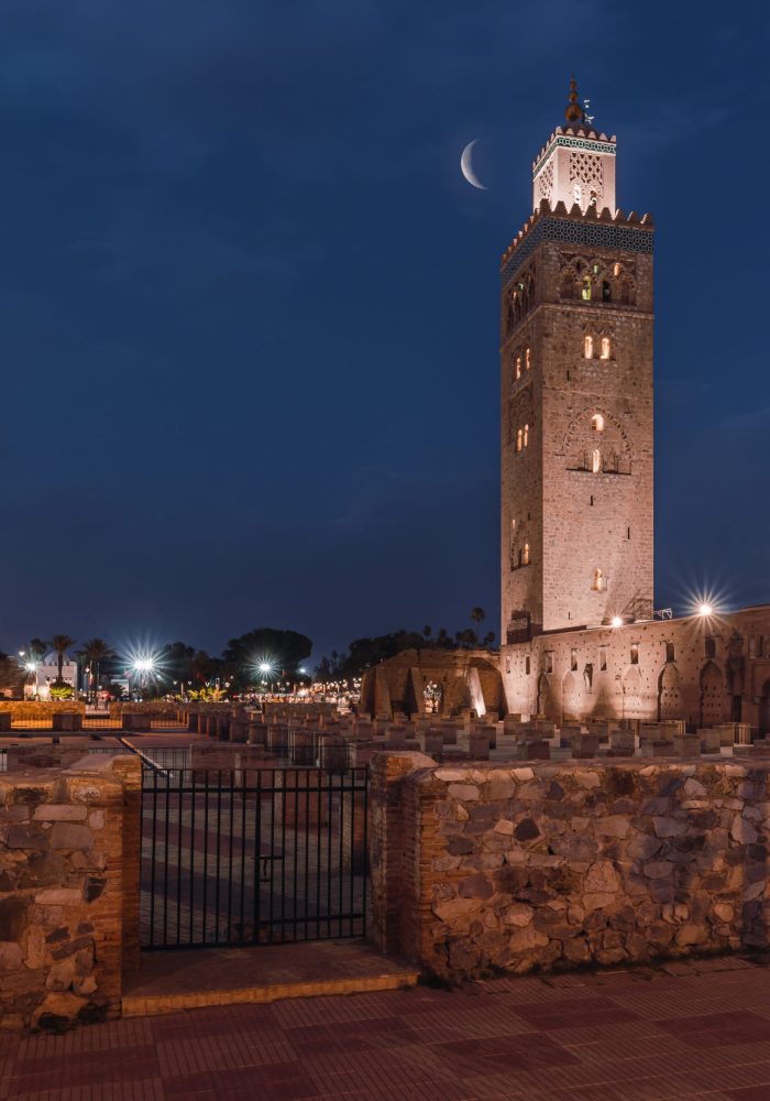 The Koutoubia Mosque at night shining under the crescent moon in Marrakesh, Marocco