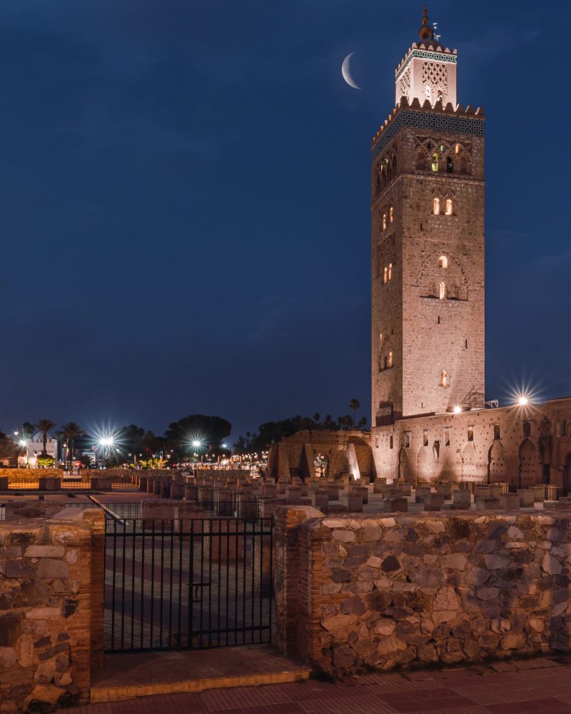 The Koutoubia Mosque at night shining under the crescent moon in Marrakesh, Marocco